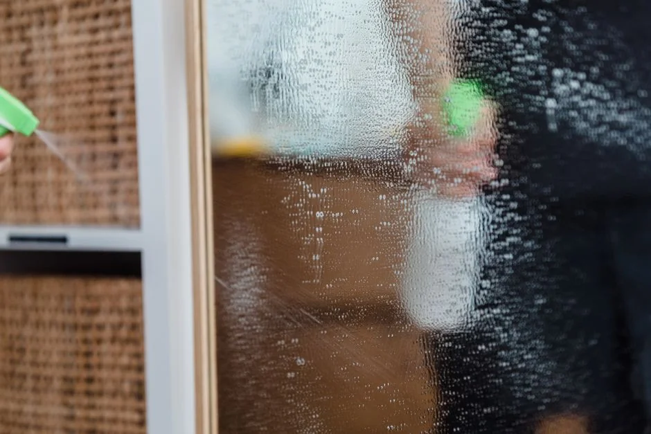 who-we-are A person in full PPE disinfecting a table indoors for hygiene and safety.